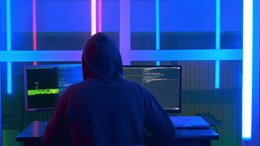 Back View Of Hacker In A Black Jacket And A Hood